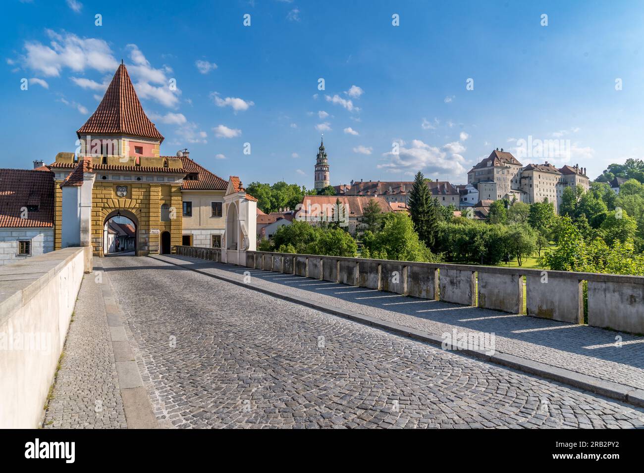 Cesky Krumlov, cancello giallo delle mura della città con ponte sul fossato, sotto il castello gotico Foto Stock