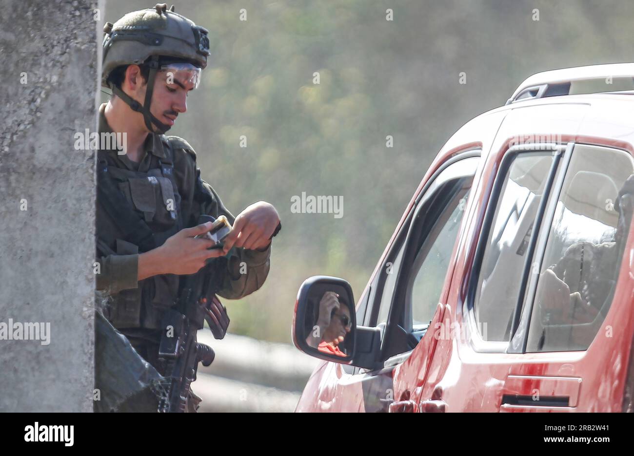 Nablus, Palestina. 6 luglio 2023. Un soldato israeliano controlla i telefoni dei palestinesi che passano attraverso un punto militare israeliano, vicino al luogo in cui è stato sparato un soldato israeliano alla porta dell'insediamento ebraico di Kedumim in Cisgiordania. Un palestinese ha effettuato un attacco di rogo e sparatoria contro un soldato israeliano, che ha portato alla sua morte. Le forze dell'esercito israeliano hanno inseguito l'autore e l'hanno ucciso pochi minuti dopo aver eseguito l'operazione. Credito: SOPA Images Limited/Alamy Live News Foto Stock