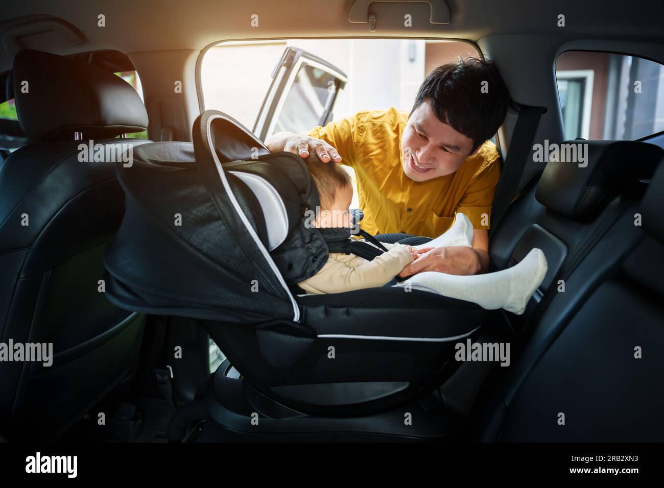 il padre si prende cura del suo bambino nel seggiolino per auto Foto Stock