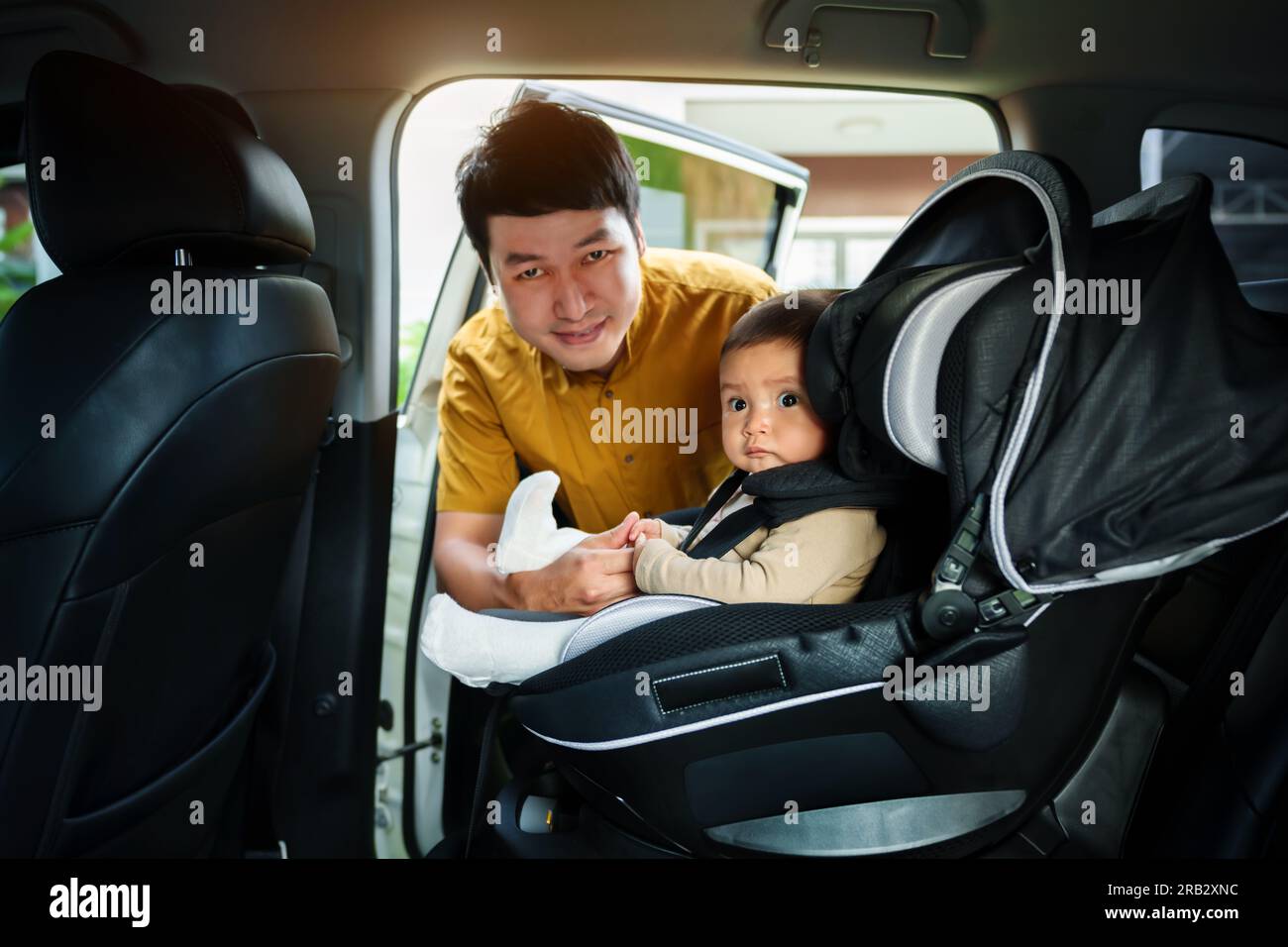 il padre si prende cura del suo bambino nel seggiolino per auto Foto Stock
