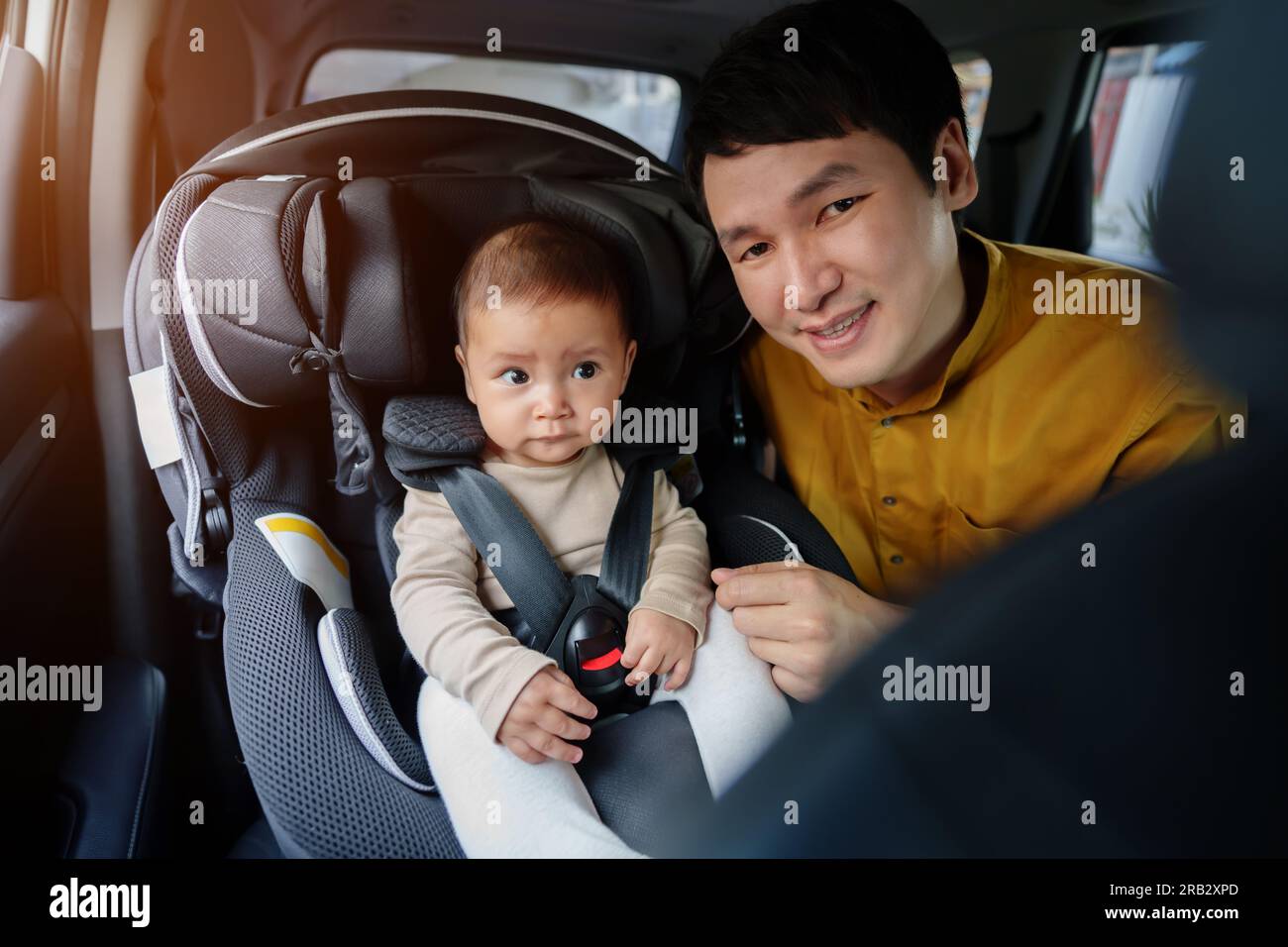 il padre si prende cura del suo bambino nel seggiolino per auto Foto Stock