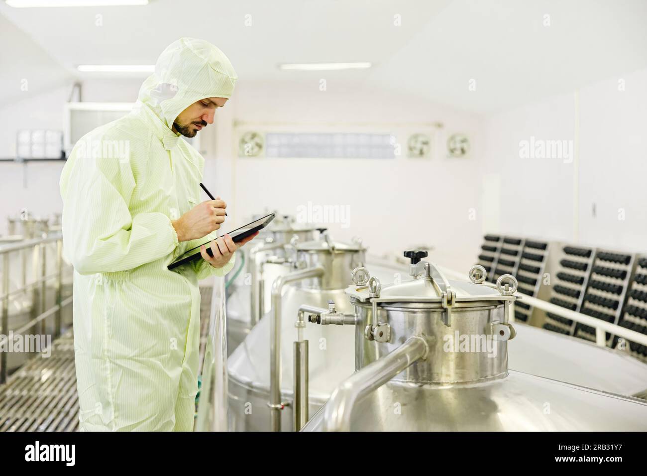 Gli addetti alle attività di Food Beverage controllano il serbatoio di fermentazione con condizioni igieniche pulite sul luogo di lavoro. Foto Stock