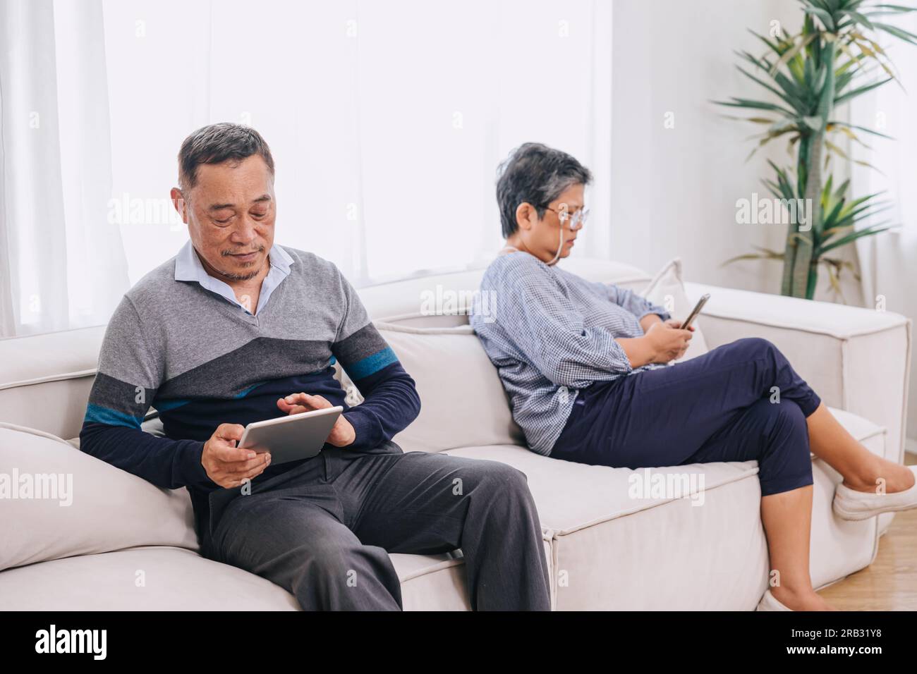 senior adulto seduto senza parlare dipendente da dispositivi con tecnologia dei social media. Dipendenza da smartphone o Internet a casa. Foto Stock