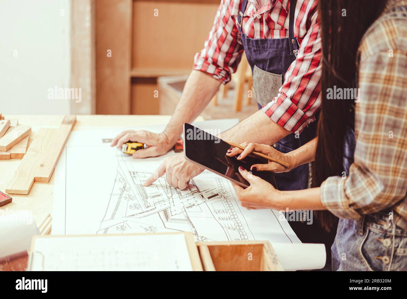 architetto professionista che lavora con la planimetria di mobili per la casa in legno e rinnova in officina consultando con il team di ingegneri. Foto Stock