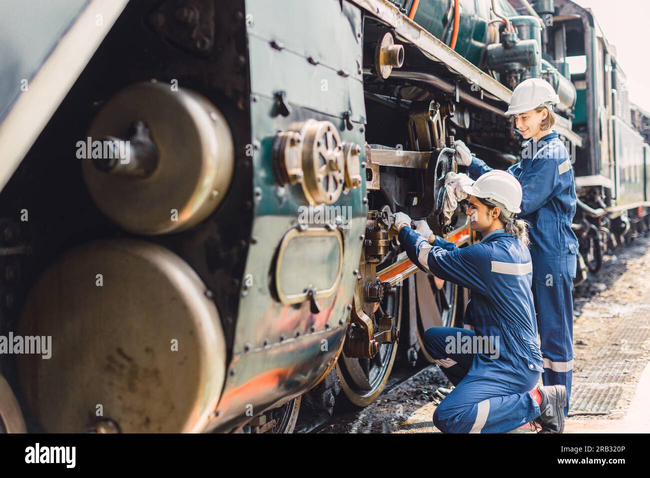 Train Engineer team di lavoro servizio manutenzione vecchio sporco vintage classico locomotiva a vapore in officina di riparazione treni alla stazione ferroviaria. Foto Stock