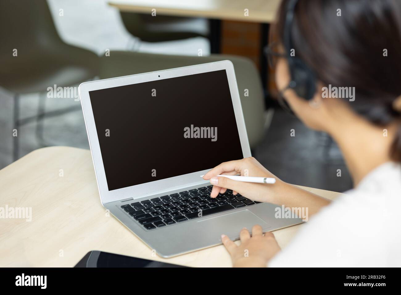 Persone che lavorano su un computer portatile con uno schermo vuoto per la creazione di immagini di testo pubblicitarie sovrapposte sulla scrivania dell'ufficio, vista posteriore di una donna d'affari che usa le mani occupate Foto Stock