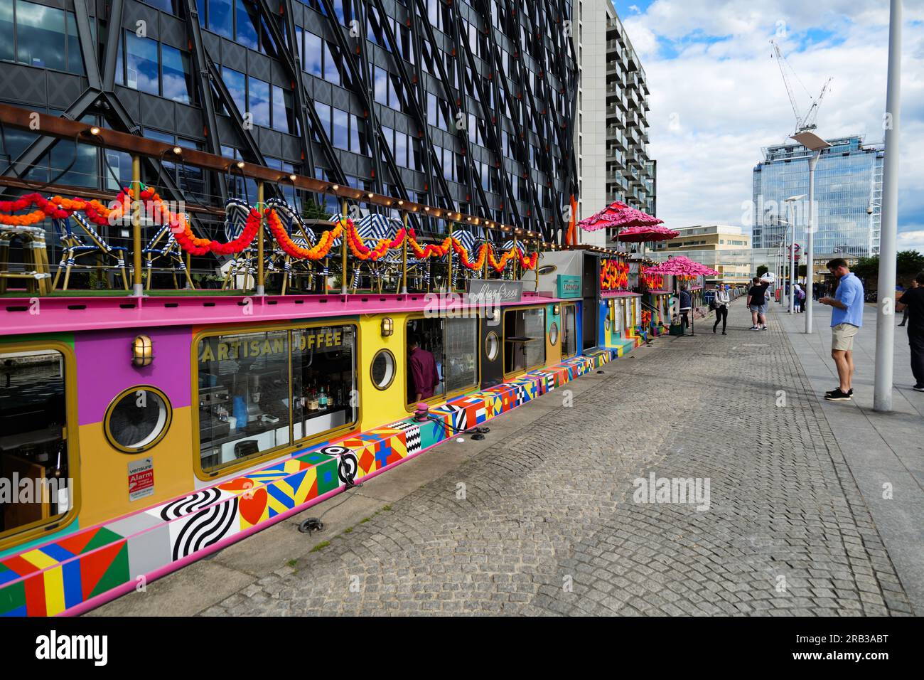 Londra - 05 28 2022: Vista da Paddington Basin con ristorante su una casa galleggiante multicolore Foto Stock Londra - 05 28 2022: Vista da Paddington Basin con ristorante su una casa galleggiante multicolore Foto Stock