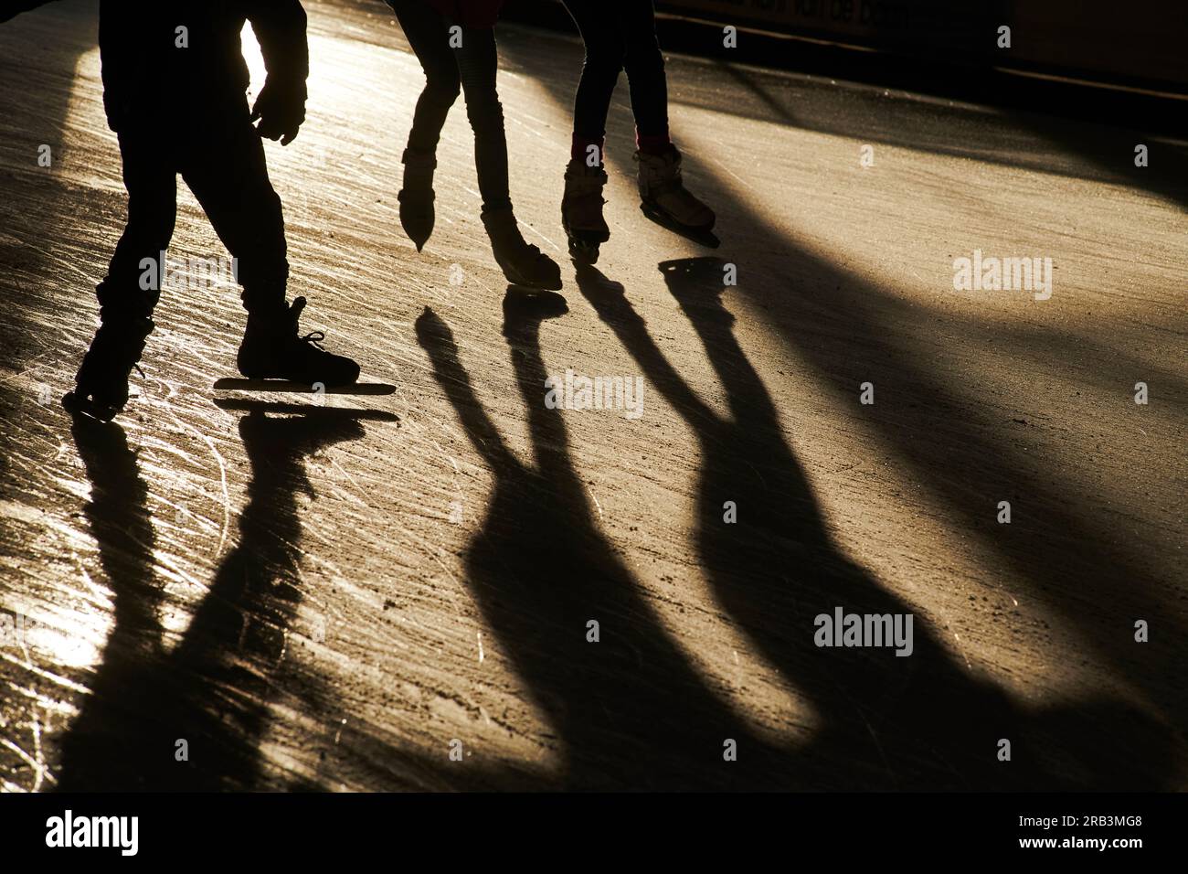 Silhouette di persone sui pattini di ghiaccio in inverno freddo sole Foto Stock