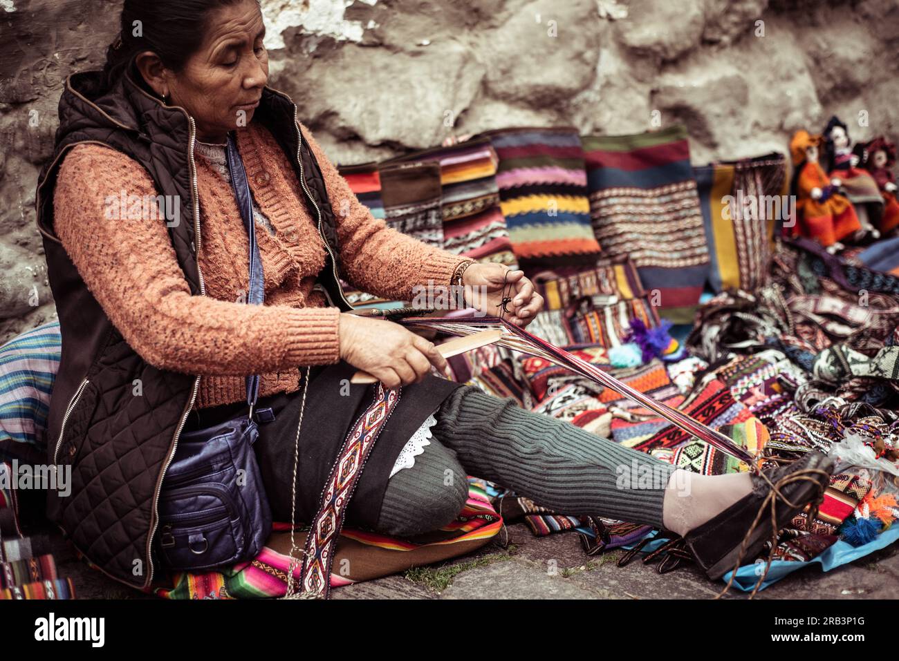 Donna locale, tessitrice tradizionale siede e si intreccia sul lato della strada di pietra Foto Stock