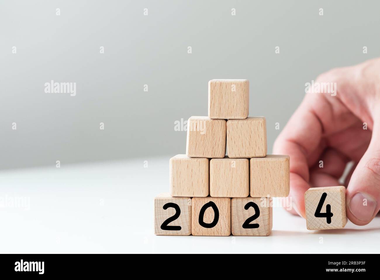 2024 Happy New Year eve blocchi di legno flip change mano sfondo blu. Conto alla rovescia a partire dalla fine del calendario delle azioni 2023 strategia visione futura Foto Stock