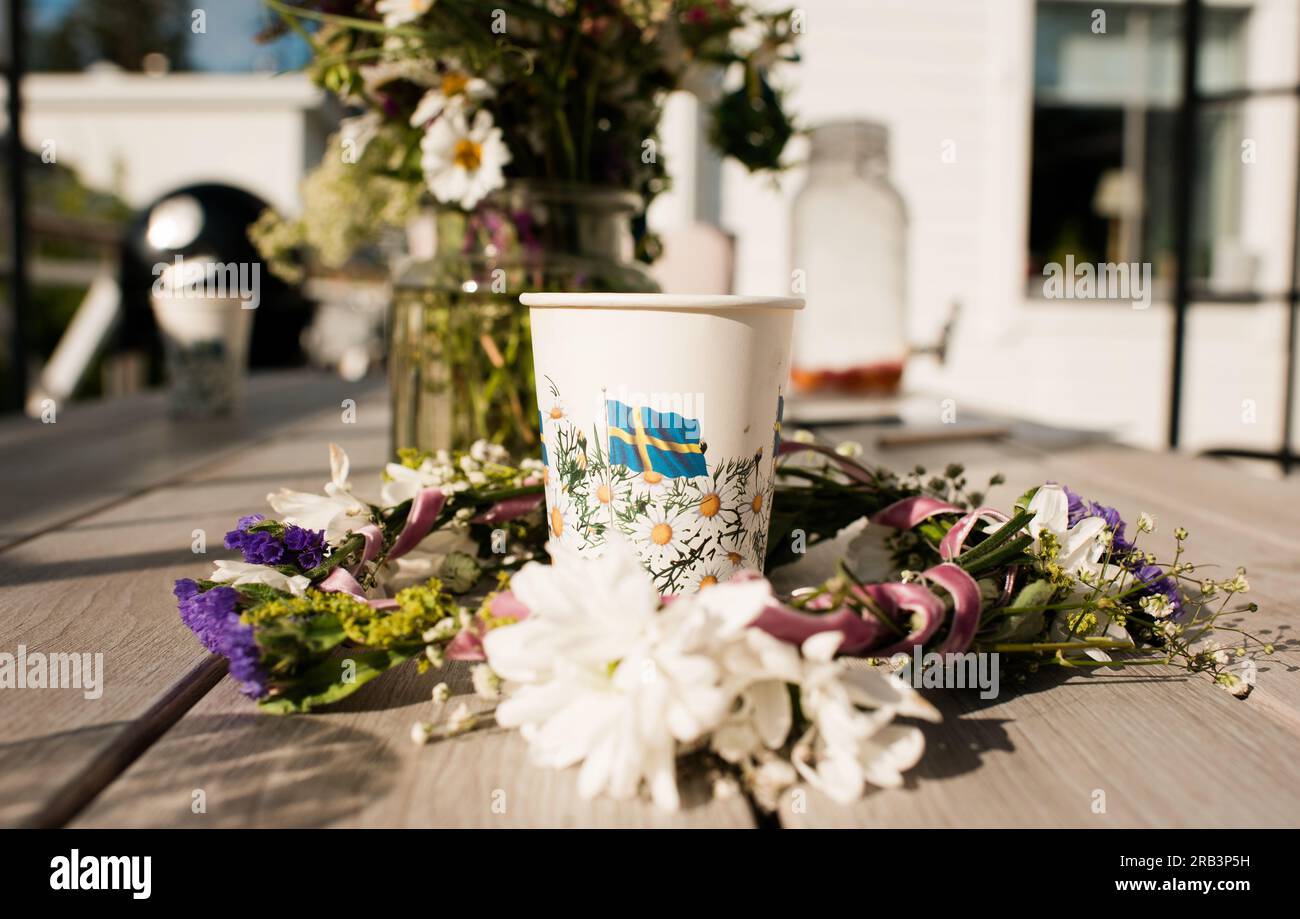 Tazza di carta su un tavolo all'aperto durante una festa di mezza estate in Svezia Foto Stock
