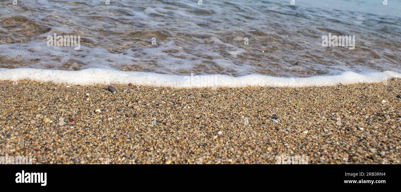 Primo piano di Pebble Beach con Light Reflecting on Stones. Pebble Beach e Sea Waves. Foto Stock