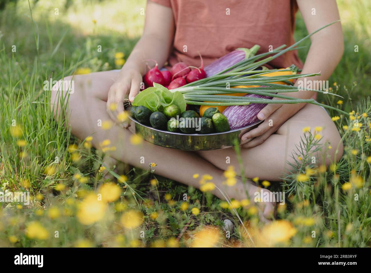 ragazza adolescente con verdure raccolte nel giardino estivo dietro la casa Foto Stock