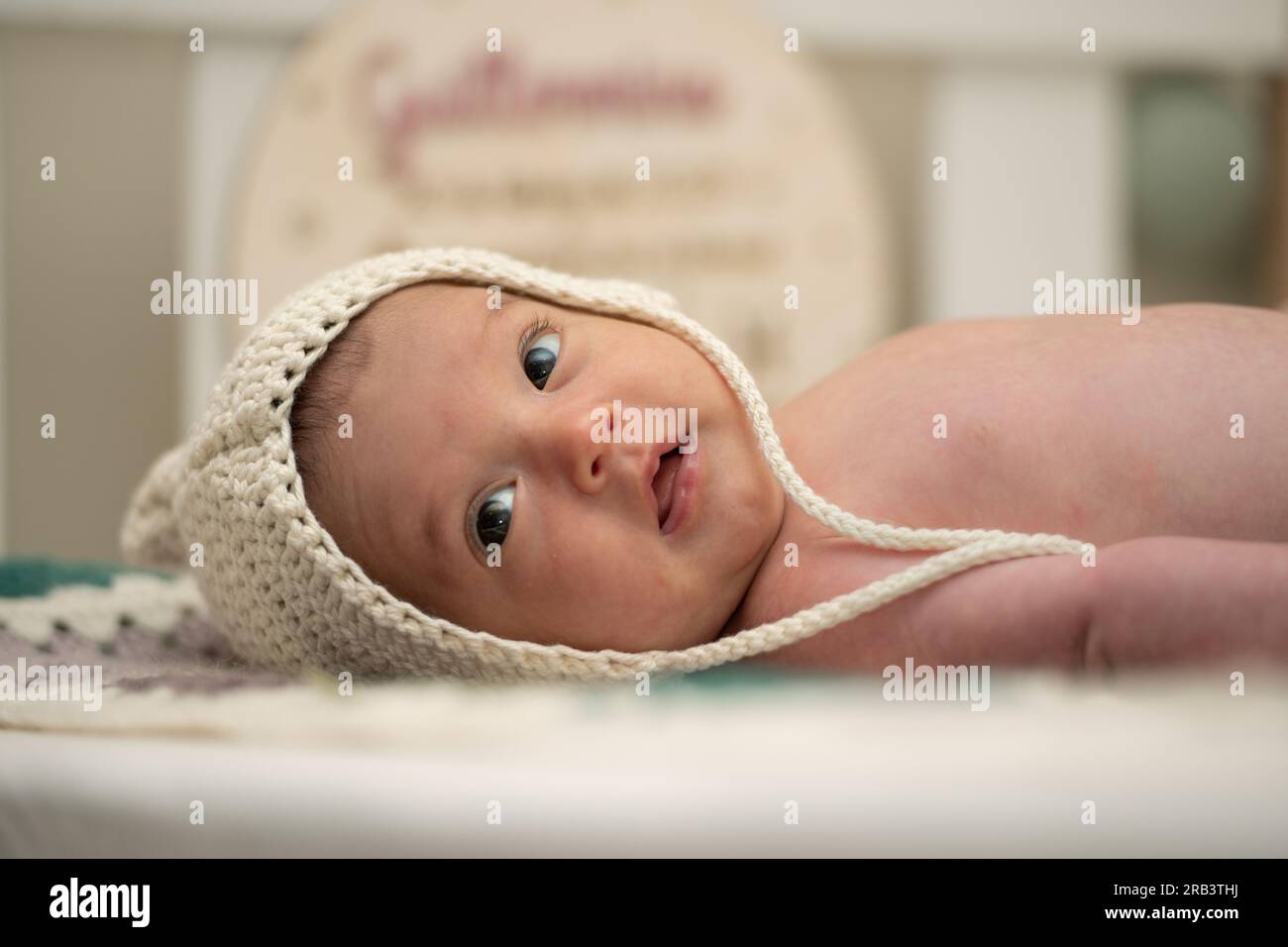 Bambino con due mesi di vita nel suo presepe con un cappuccio di lana. Foto Stock