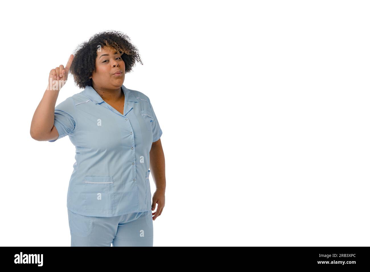 la giovane donna latina afro in uniforme blu è in piedi con il dito in alto e ha un'idea, sfondo bianco con spazio per la copia Foto Stock