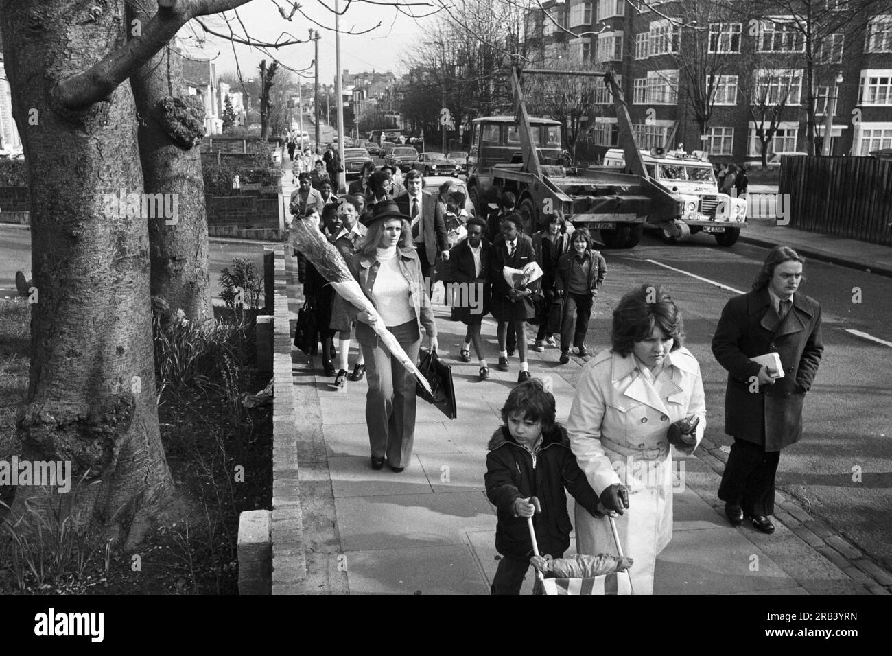 I bambini curiosi guardano la WPC Elaine Bishop, 21 anni, vestita con abiti simili a quelli indossati da Killed Playboy Bunny Girl Eve Stratford, rievocano la sua ultima passeggiata ripercorrendo i passi di Eve dalla stazione della metropolitana locale all'appartamento di Lyndhurst Drive, nella zona est di Londra. SI PREGA DI NOTARE CHE QUESTA NON È UN'IMMAGINE DI EVE STRATFORD Foto Stock