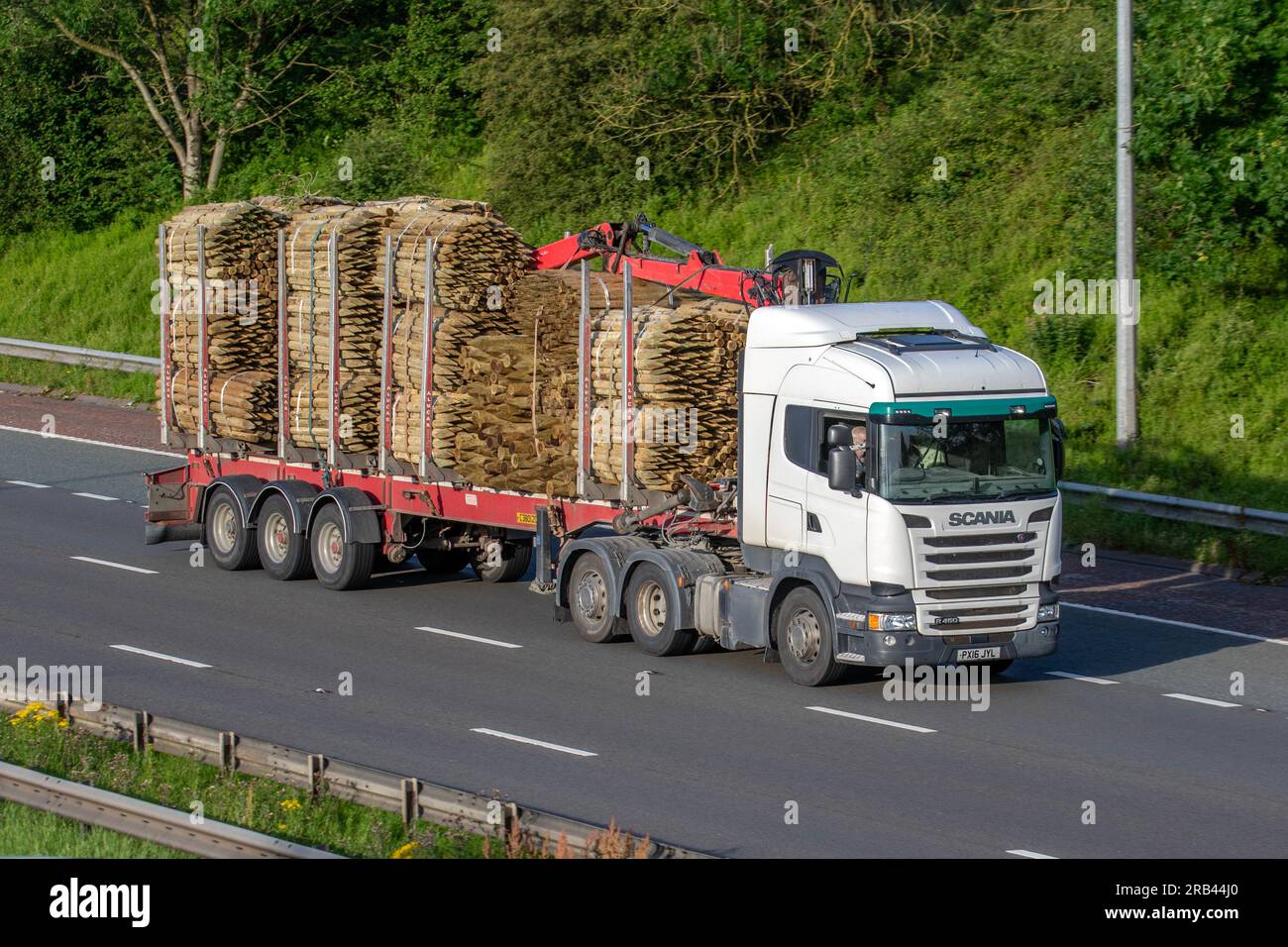 Fasci di picchetti di legno o di picchetti di legno. Tronco da recinzione del dumper Scania White Diesel da 2740 cc a pala ribassata; viaggia sull'autostrada M6 a Greater Manchester, Regno Unito Foto Stock