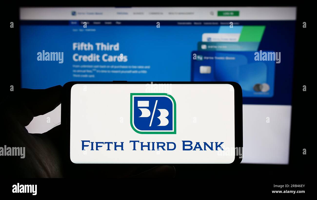 Persona che possiede uno smartphone con il logo della società finanziaria Fifth Third Bancorp (Banca 53) sullo schermo di fronte al sito Web. Concentrarsi sul display del telefono. Foto Stock