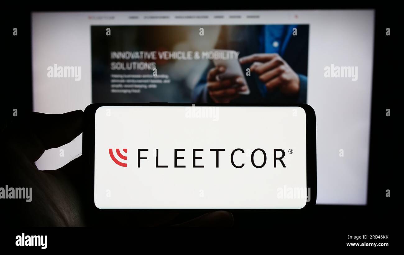 Persona in possesso di un cellulare con il logo della società finanziaria statunitense FLEETCOR Technologies Inc. Sullo schermo davanti alla pagina Web. Concentrarsi sul display del telefono. Foto Stock