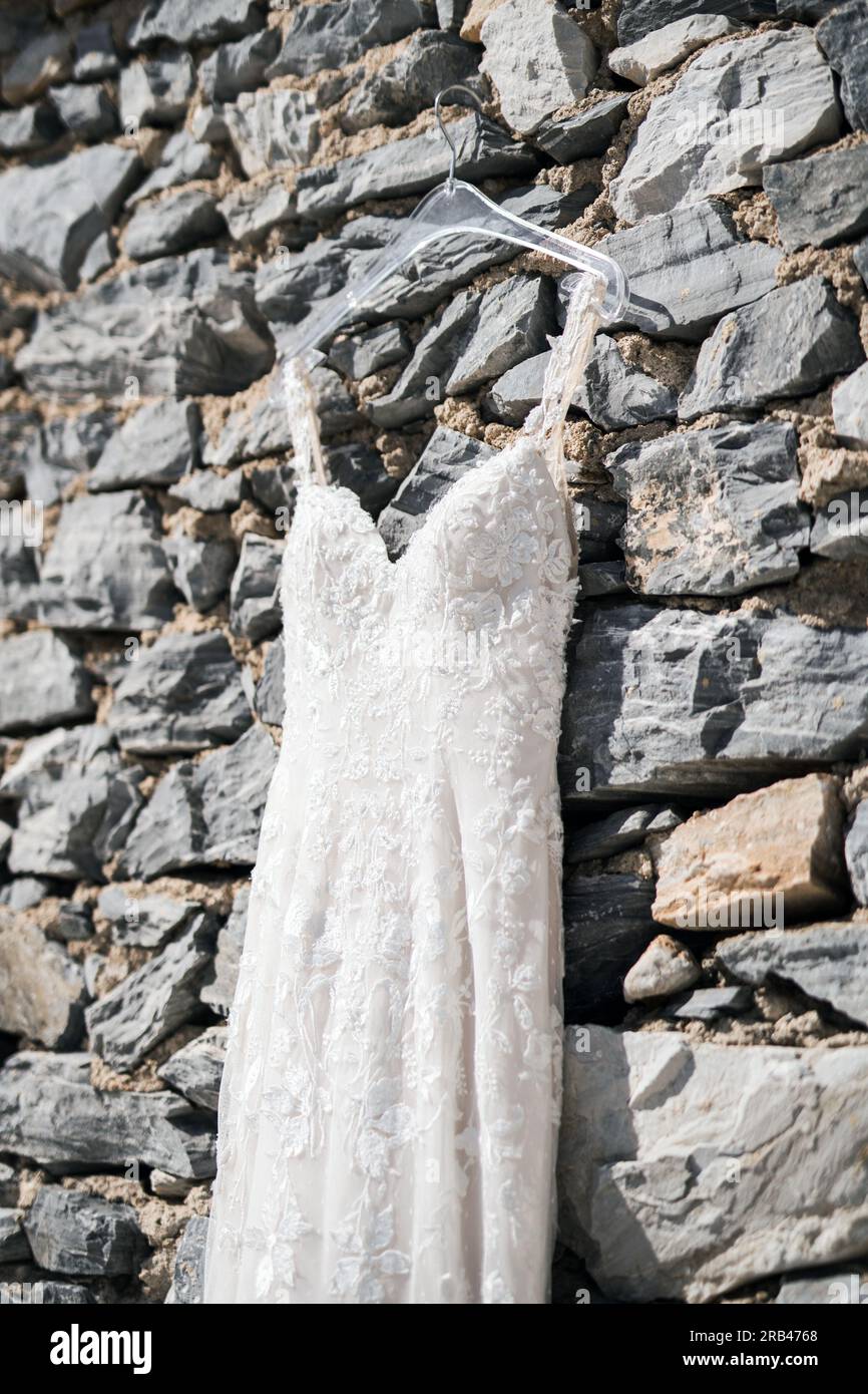 Ein wundervolles Hochzeitskleid hängt an einer traditionellen Steinwand Foto Stock