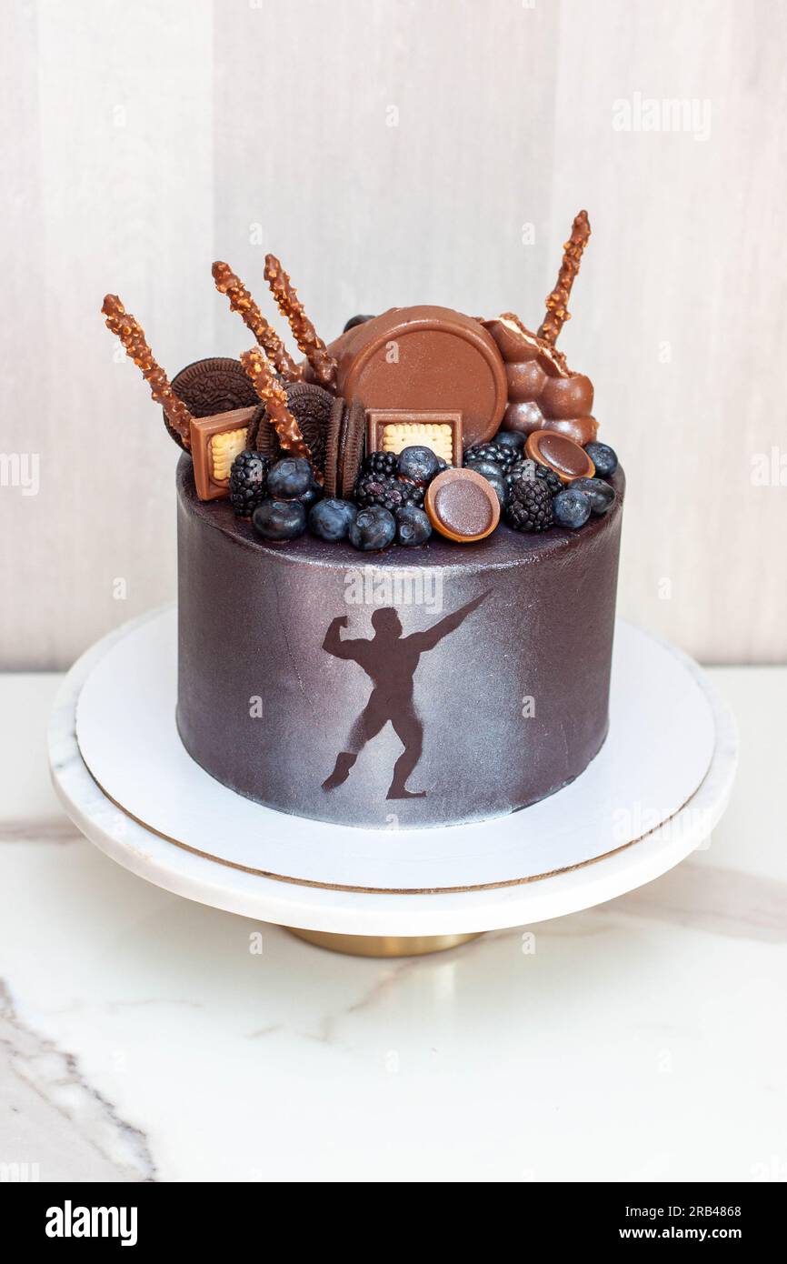 L'idea di una torta di compleanno per un bodybuilder, un atleta, un sollevatore elettrico o un maratoneta. Torta decorata con frutti di bosco freschi e cioccolato Foto Stock