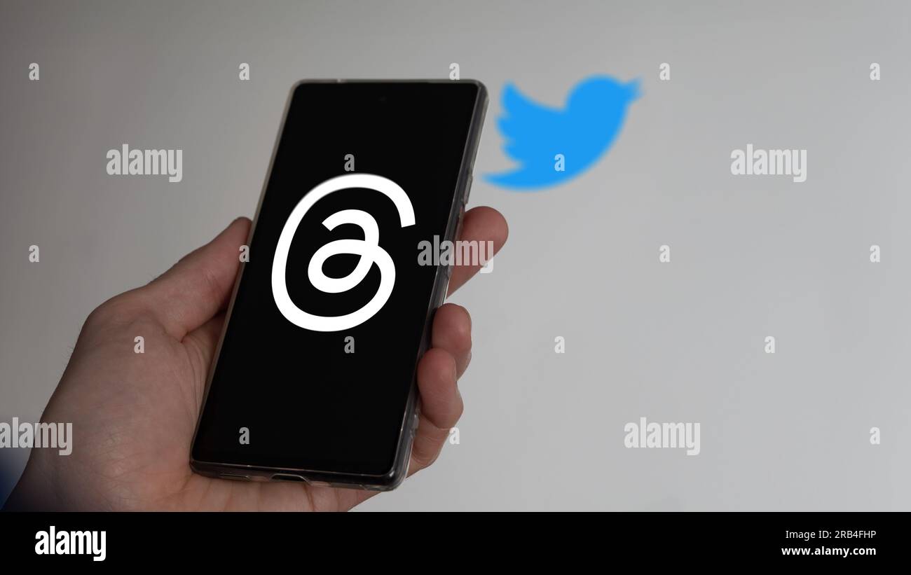 7 luglio 2023, una mano che regge un telefono, il logo dei fili sullo schermo. Sullo sfondo il logo sfocato di Twitter. Foto Stock