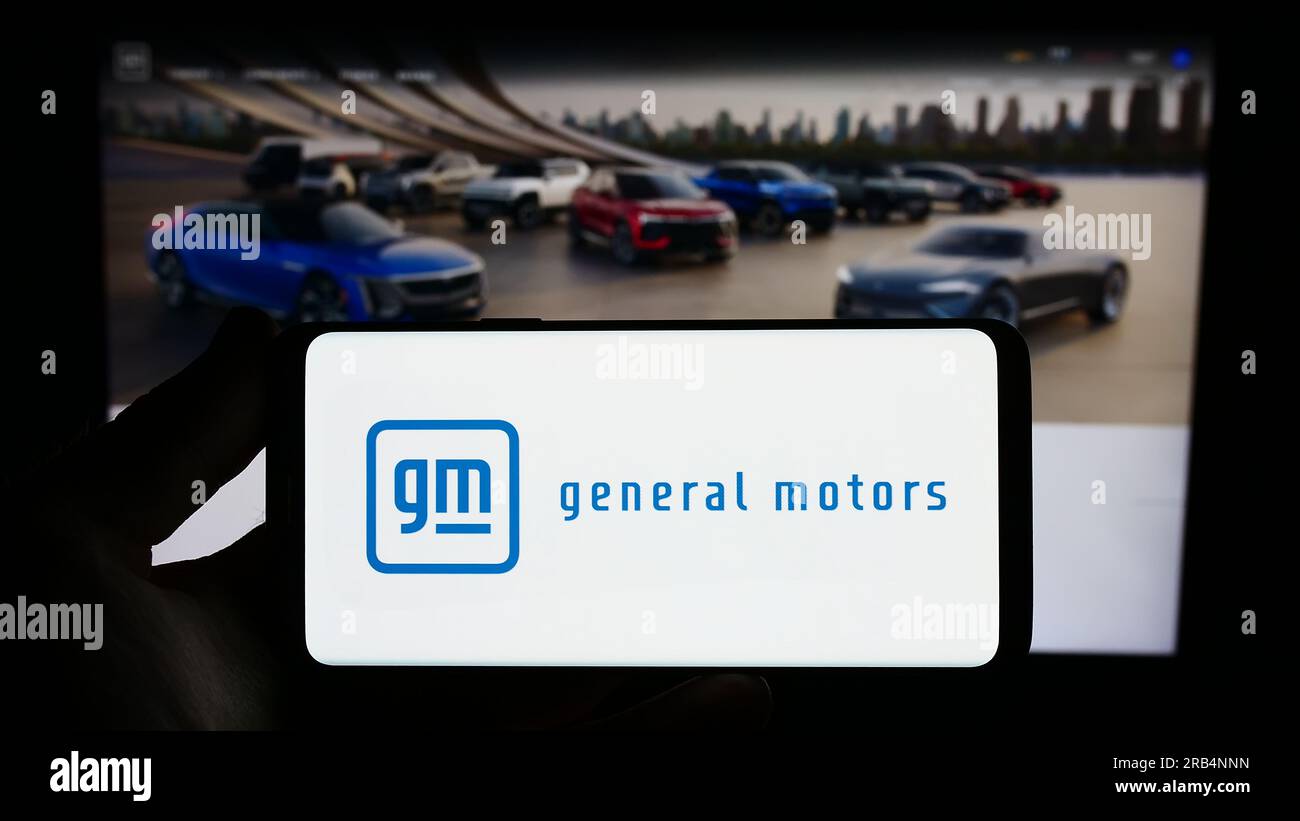 Persona che possiede uno smartphone con il logo del produttore automobilistico statunitense General Motors Company (GM) sullo schermo davanti al sito Web. Concentrarsi sul display del telefono. Foto Stock
