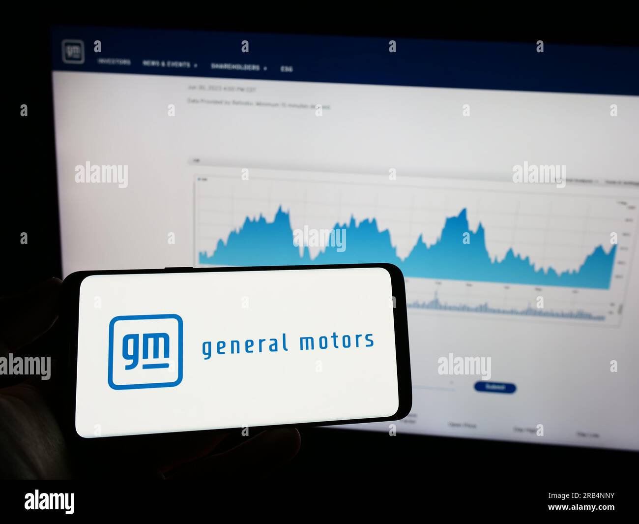Persona che possiede un telefono cellulare con il logo del produttore automobilistico statunitense General Motors Company (GM) sullo schermo davanti alla pagina Web. Concentrarsi sul display del telefono. Foto Stock