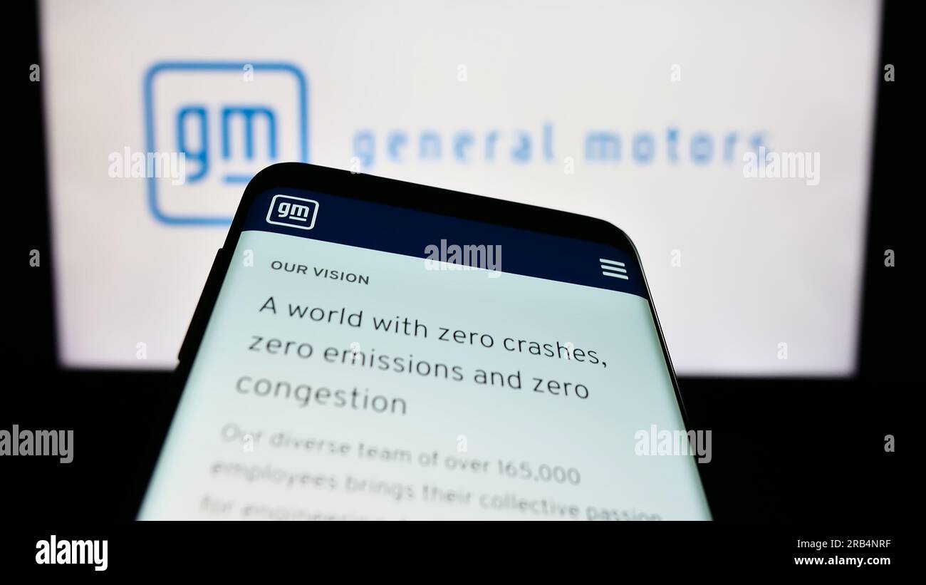 Telefono cellulare con pagina Web del produttore automobilistico statunitense General Motors Company (GM) sullo schermo davanti al logo. Mettere a fuoco in alto a sinistra sul display del telefono. Foto Stock