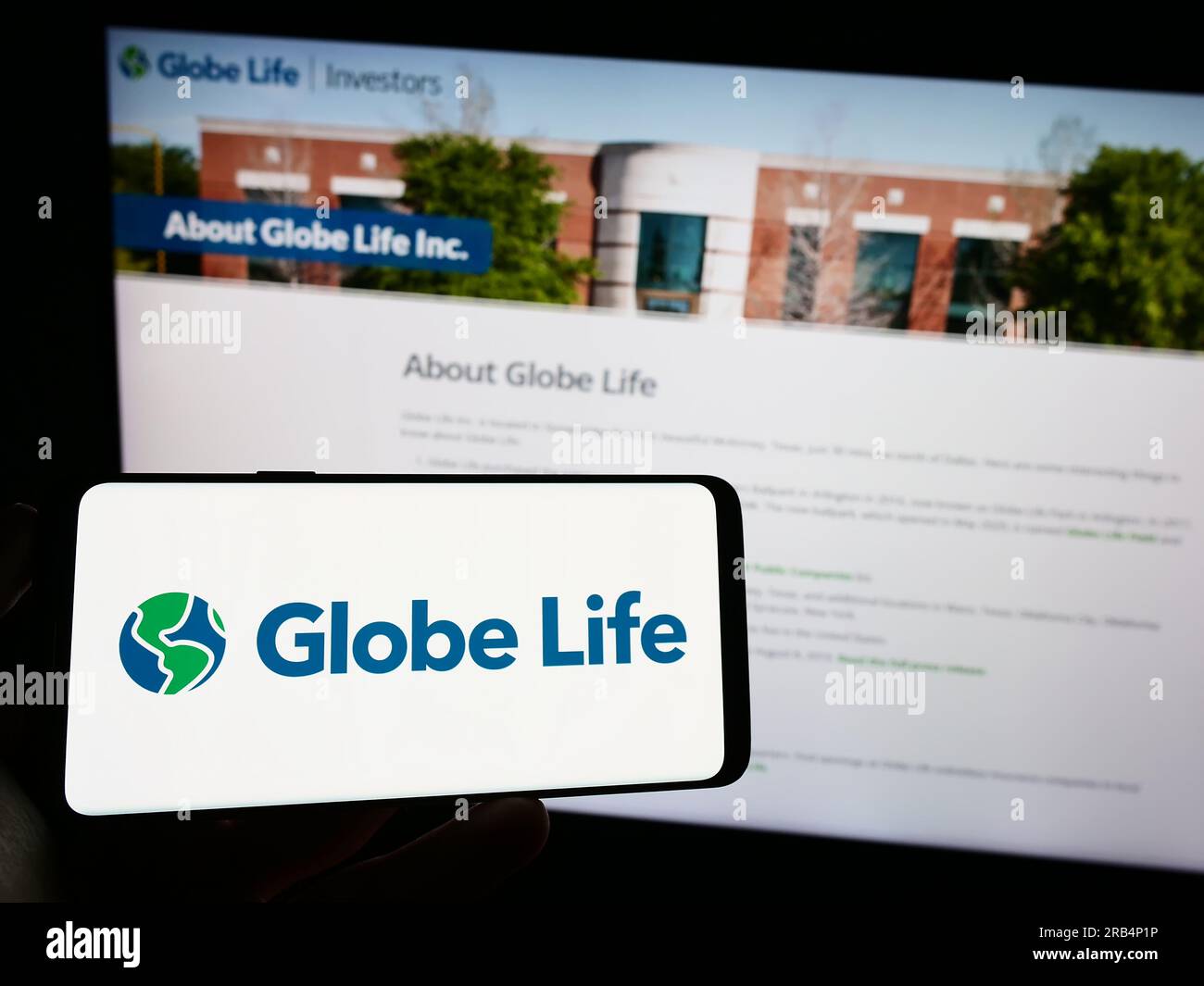 Persona che possiede un telefono cellulare con il logo della compagnia di assicurazioni americana Globe Life Inc. Sullo schermo davanti alla pagina Web. Concentrarsi sul display del telefono. Foto Stock