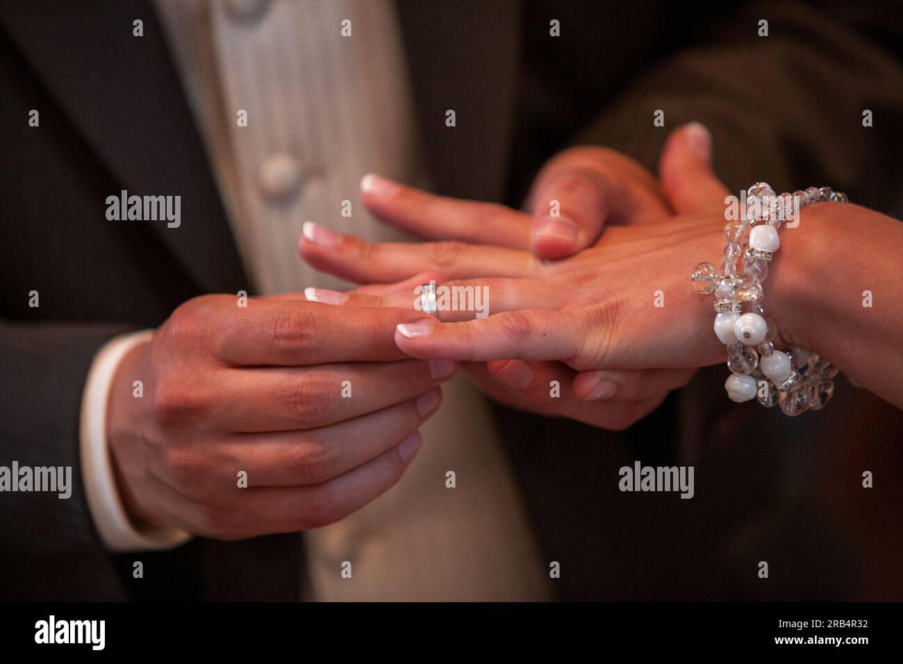 Una foto ravvicinata che cattura il momento tenero di una sposa e uno sposo amorevole che si scambiano bellissimi fedi nuziali. L'immagine evoca emozioni di impegno e devozione, incarnando il concetto di "Marry me" in modo toccante e senza tempo. Primo piano di una sposa e uno sposo amorevole che mette una bella fede nuziale all'amato partner, il concetto Marry me. Foto di alta qualità Foto Stock