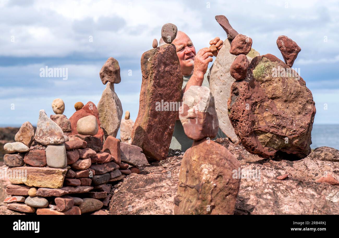 L'artista Ken Bambury, di Dundee, crea sculture in pietra sulla spiaggia di Bayswell a Dunbar, durante l'European Land Art Festival (ELAF) nell'East Lothian. Il Festival è un evento della durata di una settimana e include artisti della natura provenienti da tutto il mondo che creano disegni di sabbia, sculture in legno e pile di pietra utilizzando solo materiali trovati lungo la costa. Data immagine: Venerdì 7 luglio 2023. Foto Stock