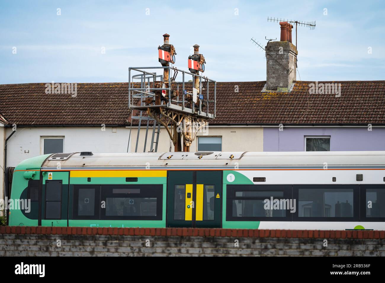 Treno Electrostar classe 377 che supera il vecchio gantry di segnali a semaforo meccanici vicino alla stazione di Littlehampton, Regno Unito, con case sullo sfondo. Foto Stock