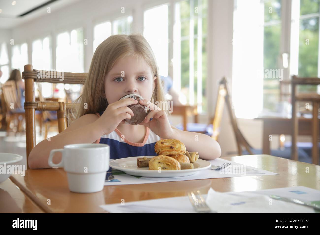 Carina bambina di 5 anni che mangia muffin al cioccolato al ristorante Foto Stock