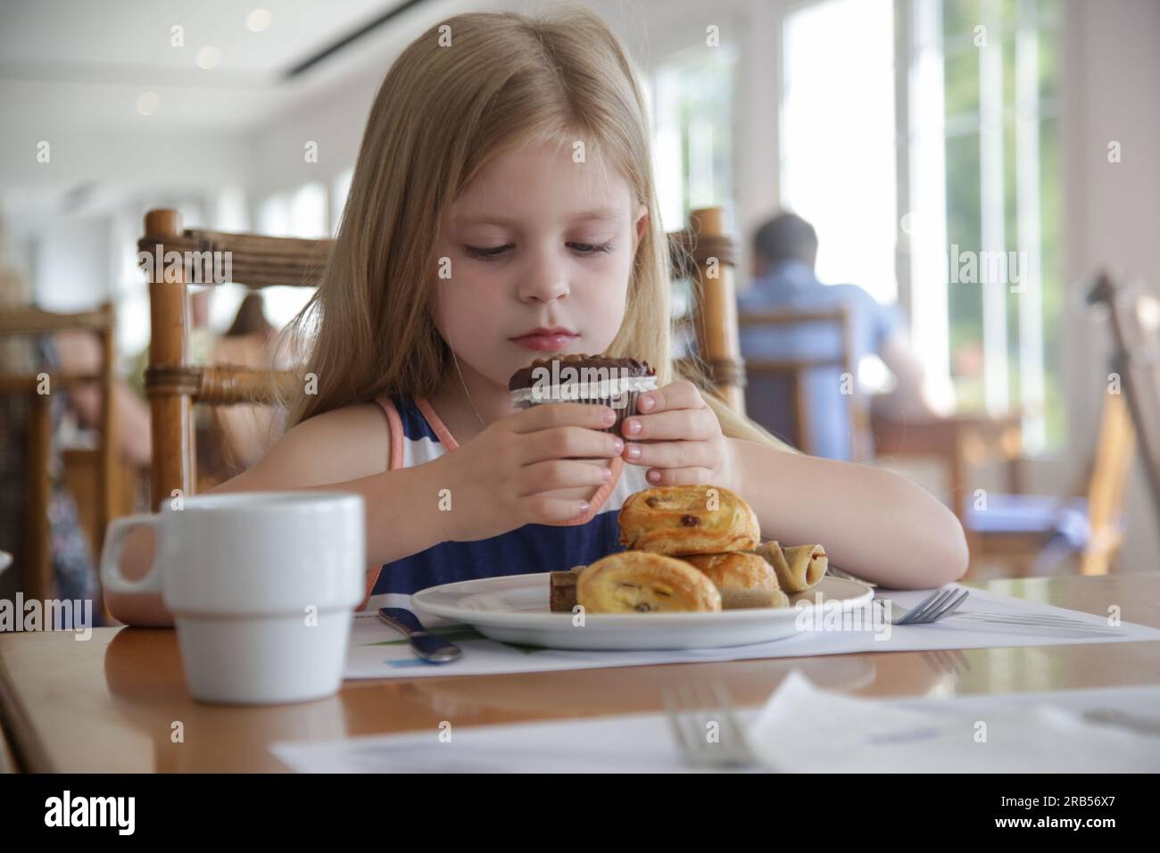 Carina bambina di 5 anni che mangia muffin al cioccolato al ristorante Foto Stock