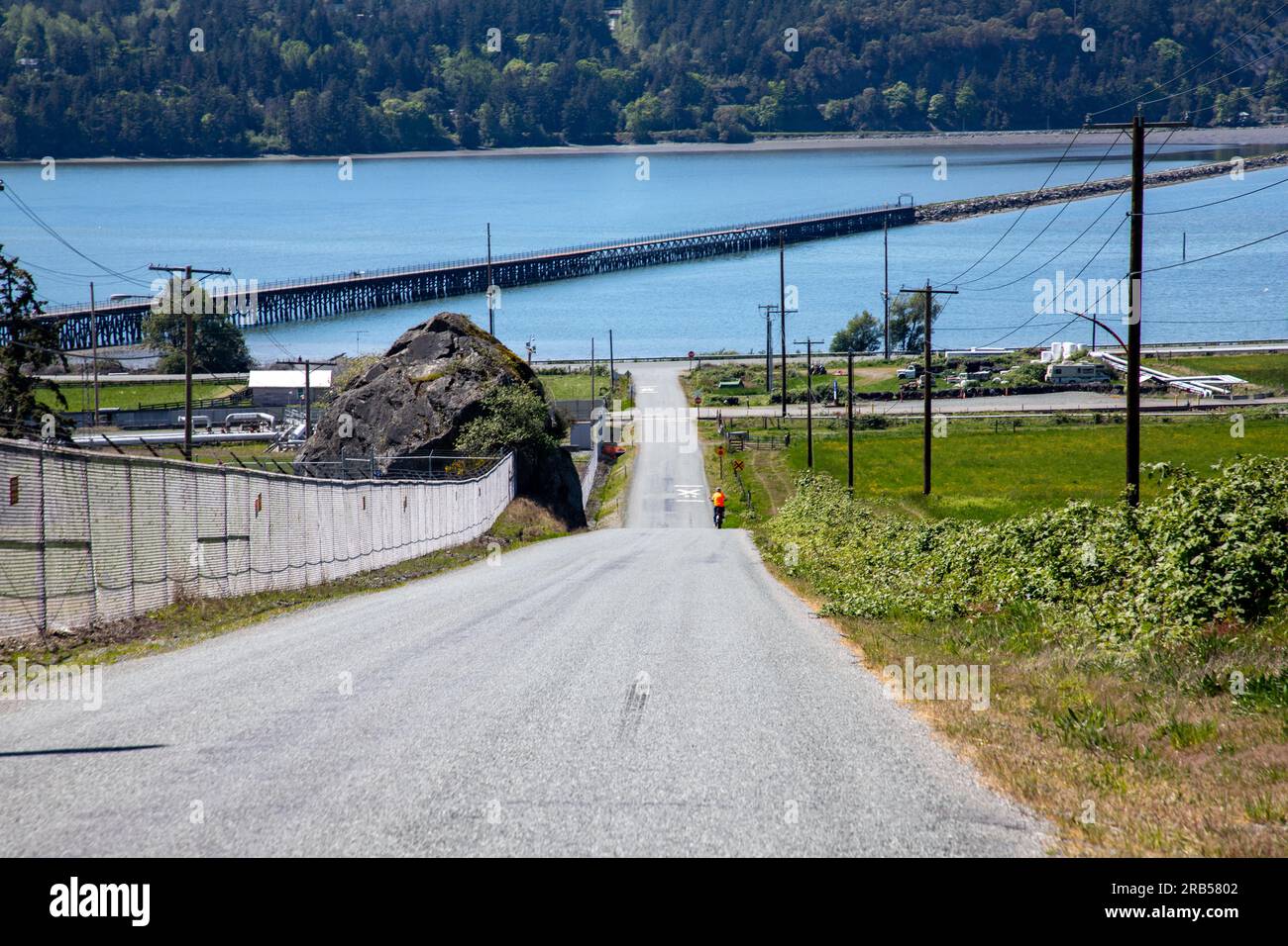 Il ciclista eBike scende lungo la strada verso il Tommy Thompson Trail sopra Fidalgo Bay Foto Stock