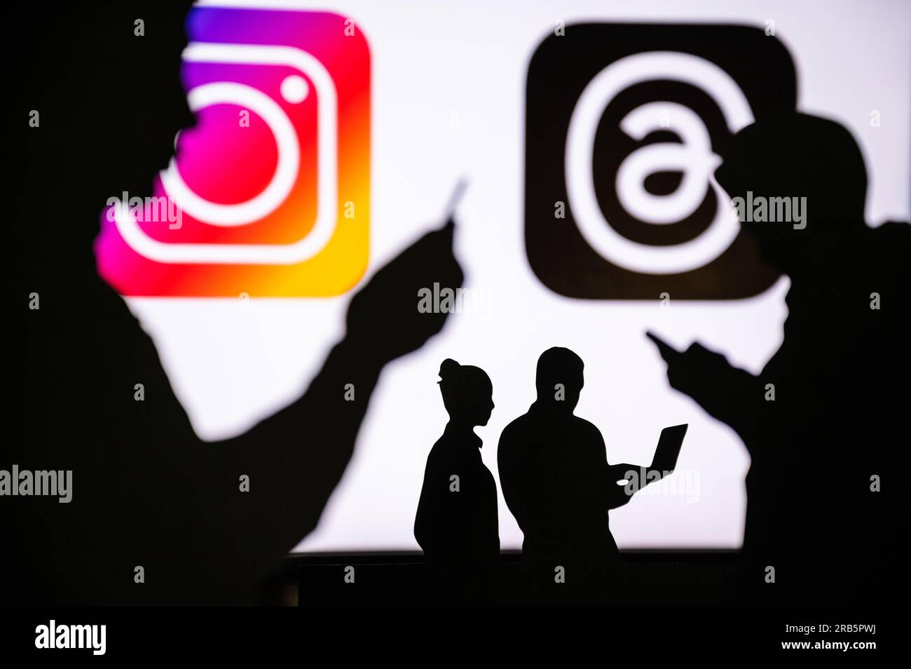 CALIFORNIA, STATI UNITI, 7 LUGLIO 2023: Threads App e logo dell'app Instagram. Silhouette di persone che chattano su dispositivi mobili e utilizzano app intelligenti e social m Foto Stock