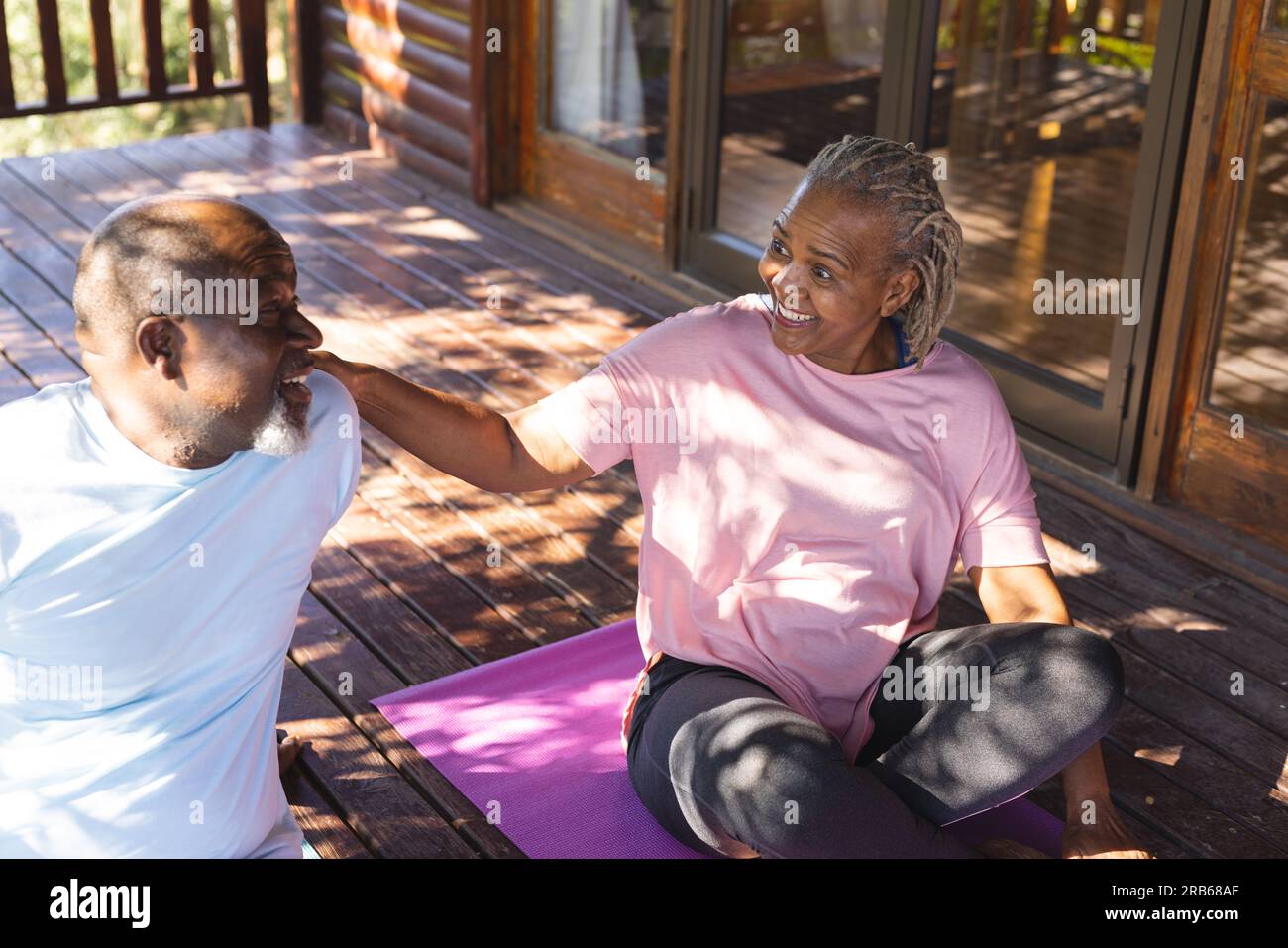 Felice coppia afro-americana che parla su tappeti in terrazza. Senior lifestyle, relax, pensione, vita sana, fitness, esercizio fisico e benessere Foto Stock