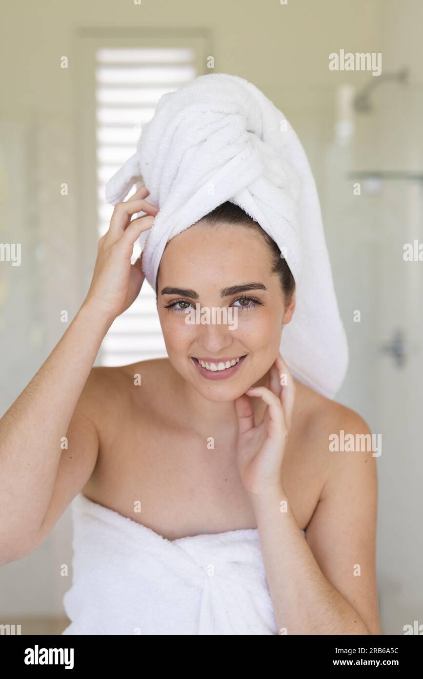 Ritratto di donna caucasica felice con un asciugamano sulla testa in bagno. Vita domestica, cura del sé e stile di vita, inalterato. Foto Stock