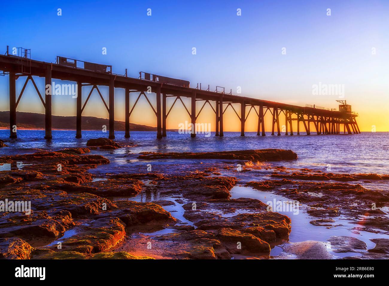 Molo storico illuminato dal sole presso la spiaggia Middle Camp della baia di Catherine Hill sulla costa del Pacifico in Australia. Foto Stock