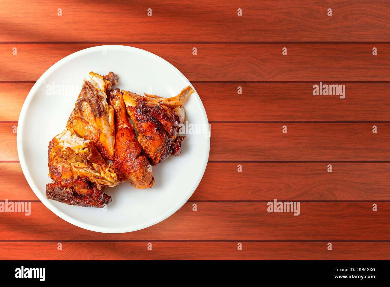 Ali di pollo grigliate su piatto bianco su sfondo di legno Foto Stock