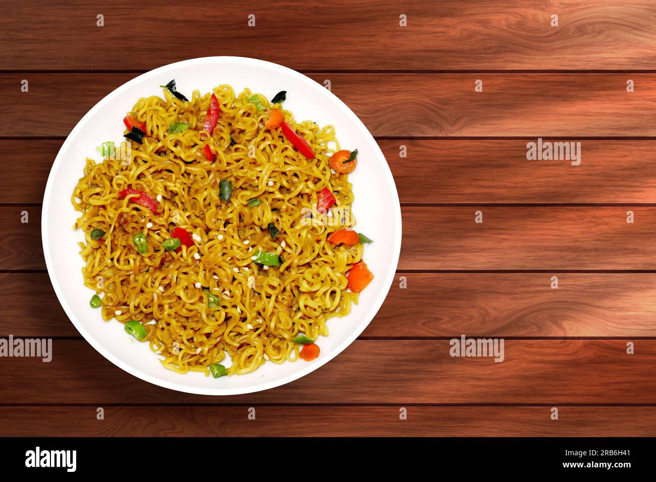 Spaghetti istantanei con verdure in un piatto bianco su sfondo di legno Foto Stock