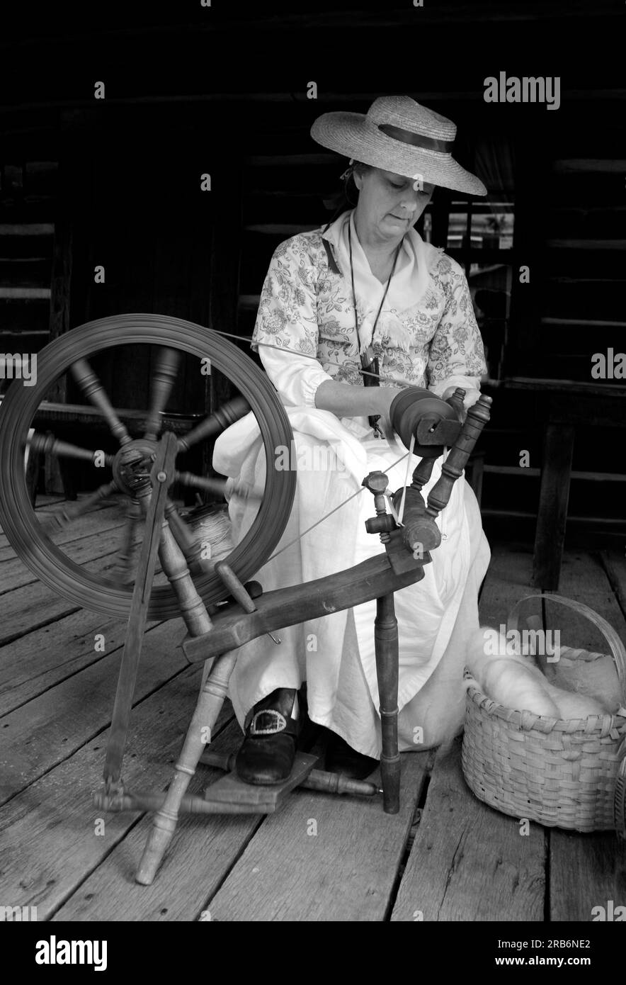 Un reenattore pioniere del XIX secolo dimostra le prime tecniche tessili della lana con una ruota rotante in un evento storico vivente ad Abingdon, Virginia. Foto Stock
