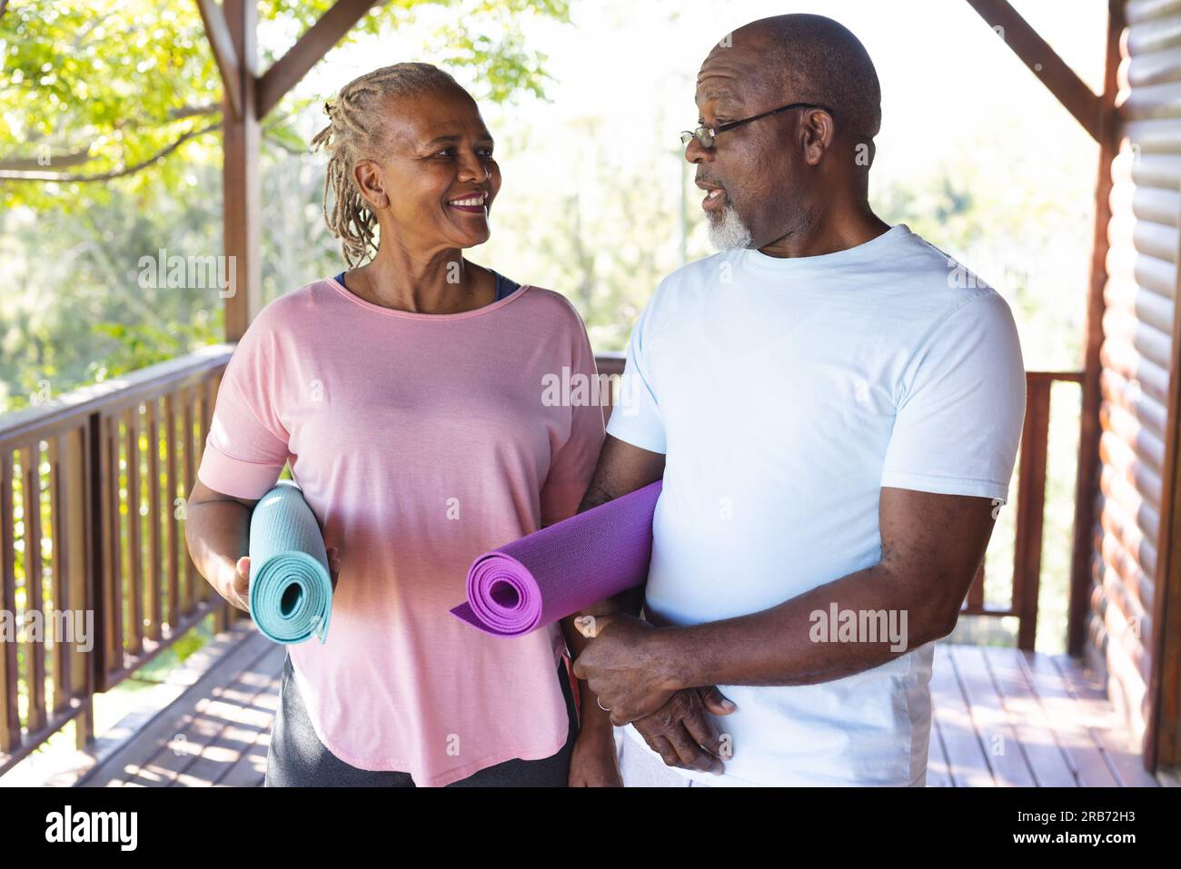 Ritratto di una felice coppia afroamericana anziana che tiene dei tappetini per esercizi yoga in terrazza. Senior lifestyle, relax, pensione, vita sana, fitness, Foto Stock