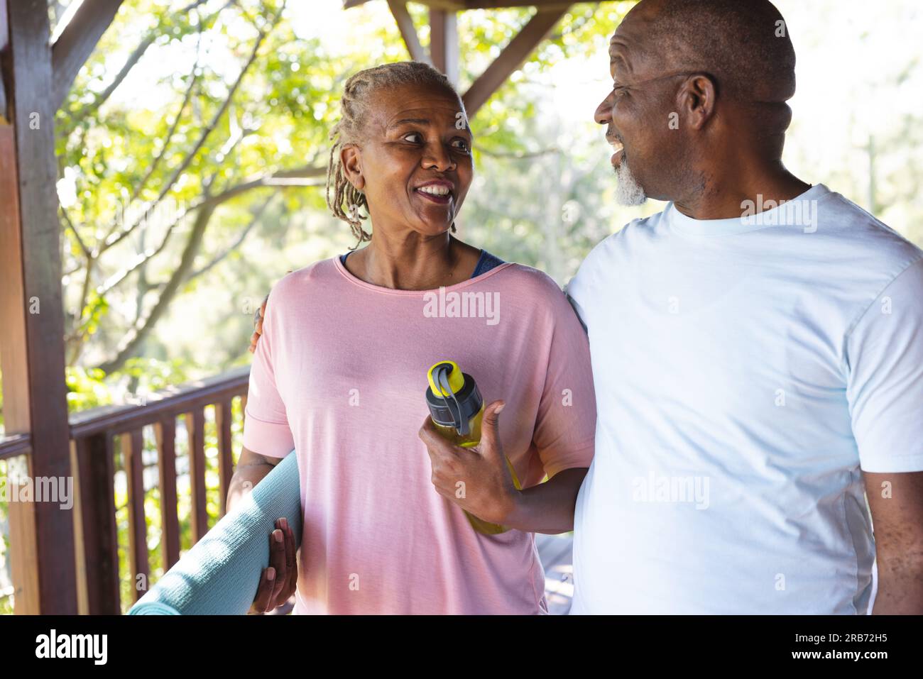 Ritratto di una felice coppia afroamericana anziana che tiene un tappetino per esercizi yoga sulla terrazza. Senior lifestyle, relax, pensione, vita sana, fitness, Foto Stock