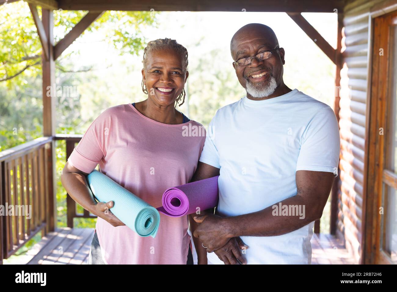 Ritratto di una felice coppia afroamericana anziana che tiene dei tappetini per esercizi yoga in terrazza. Senior lifestyle, relax, pensione, vita sana, fitness, Foto Stock
