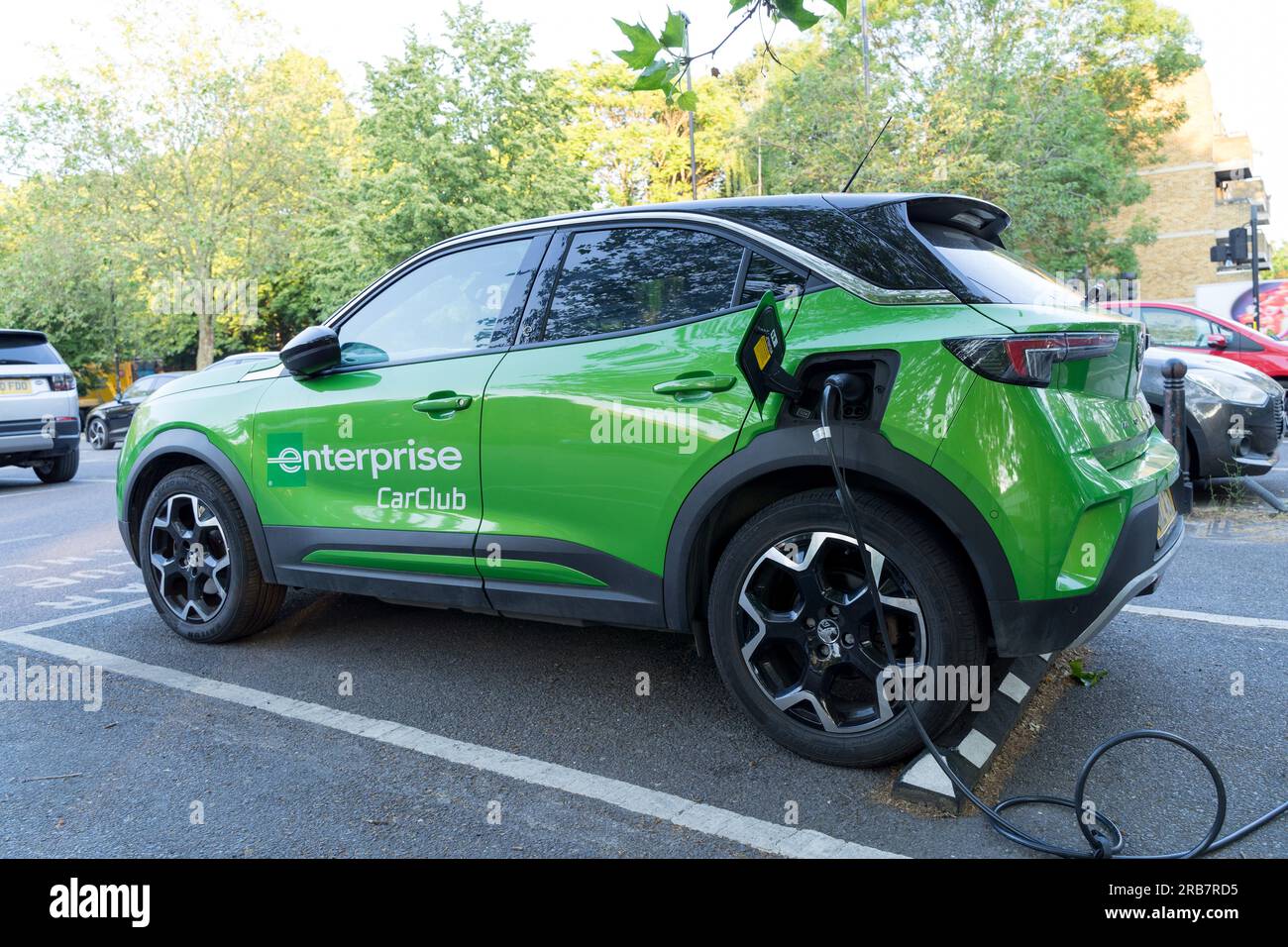 L'auto di Enterprise CarClub in verde è collegata alla stazione di ricarica elettrica installata nel parcheggio pubblico di Greenwich, Inghilterra, Regno Unito Foto Stock