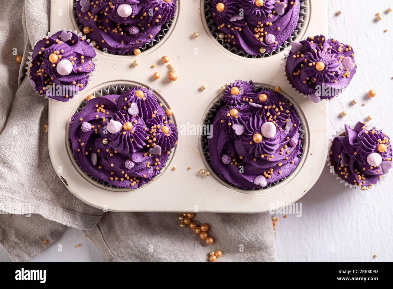 Cupcake bellissimi e unici a forma di fiore viola. Dessert viola con spruzzi dorati. Foto Stock