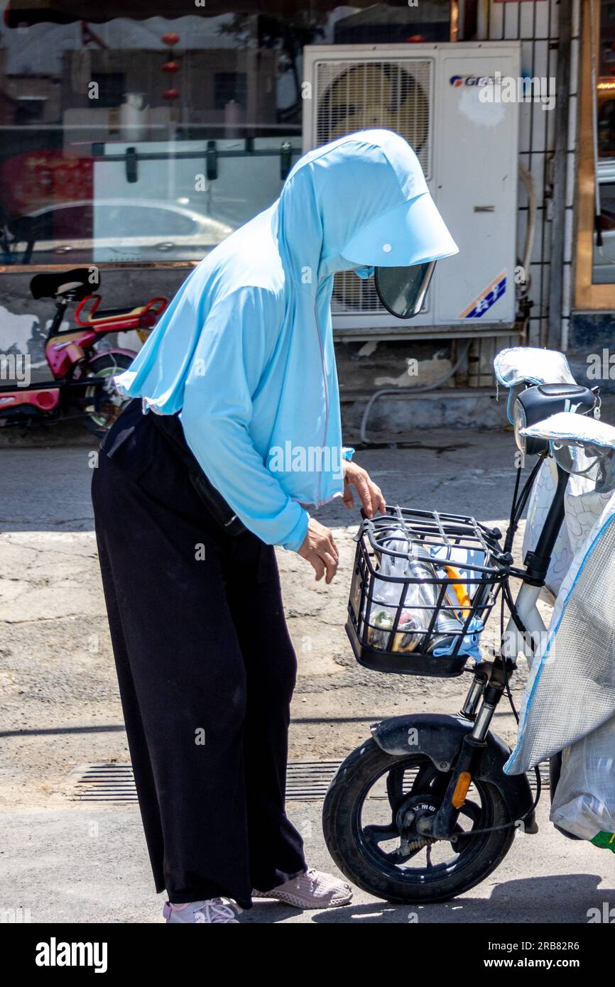 ANYANG, CINA - 8 LUGLIO 2023 - Un pedone che indossa indumenti protettivi che corre su una strada a una temperatura di 40 gradi Celsius nella contea di Hua, Anyan Foto Stock