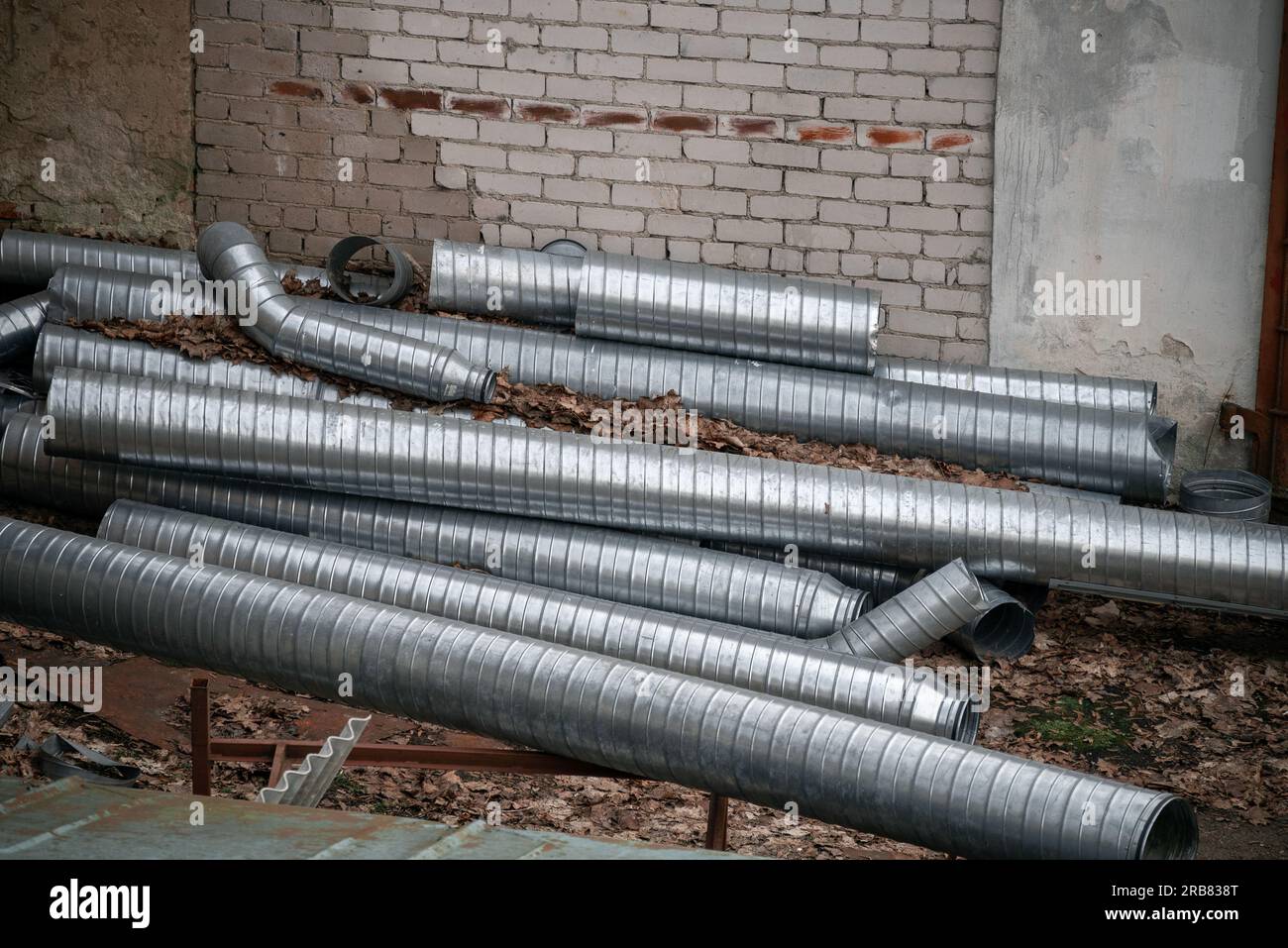 I condotti d'aria metallici a spirale vengono scaricati in un cumulo nel cortile. Foto Stock